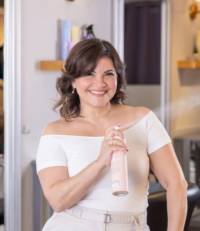 Amy, owner of Amy's Salon, holding a can of hairspray at her station