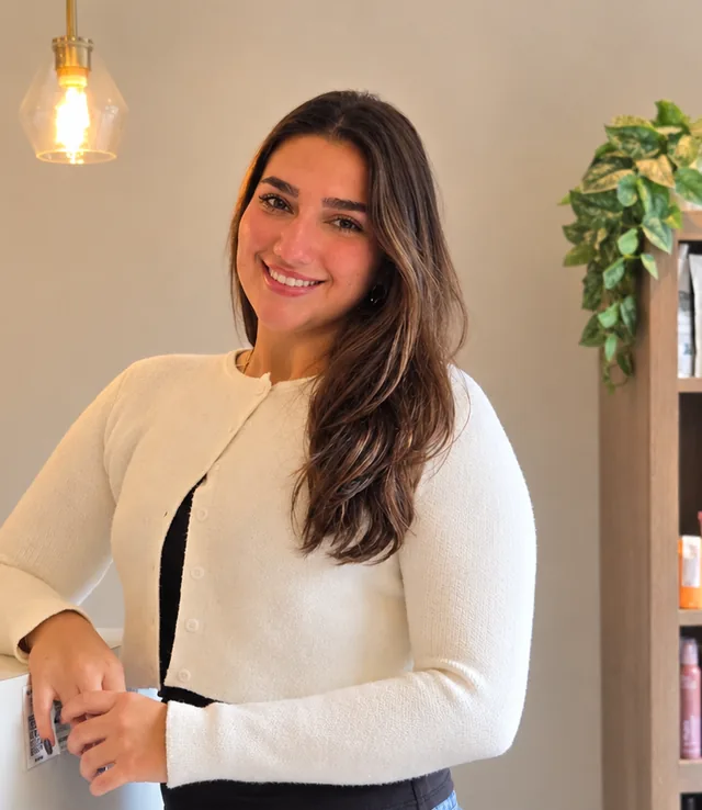 Gianna, salon assistant at Amy's Salon, smiling beside the front desk