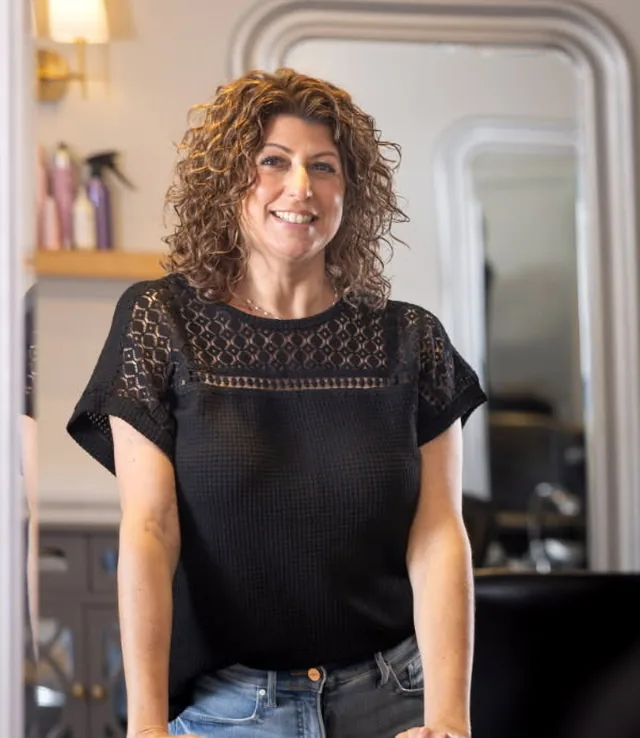 Renee, stylist at Amy's Salon, standing behind her styling chair